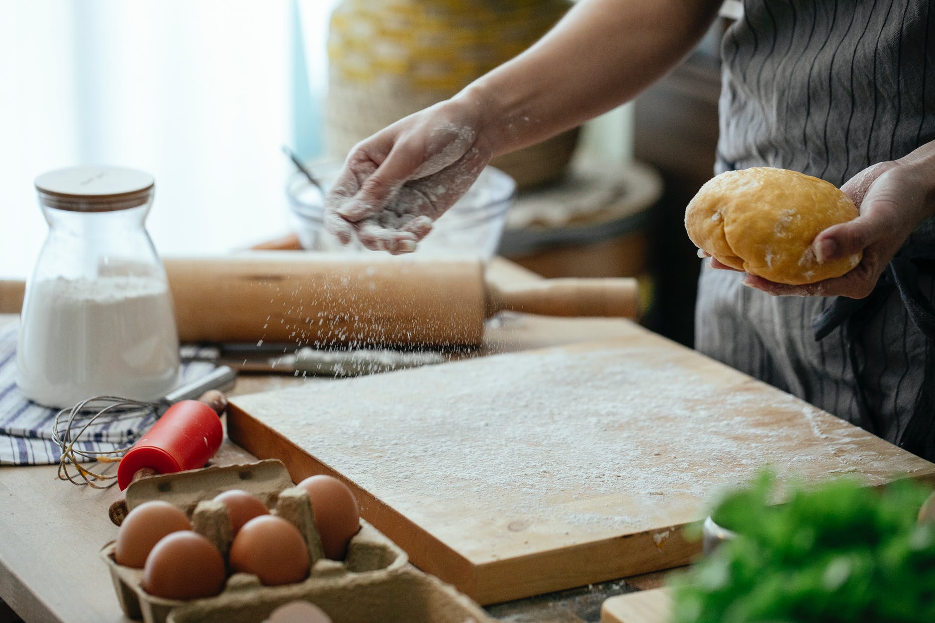 crop woman sprinkling board with flour to knead dough