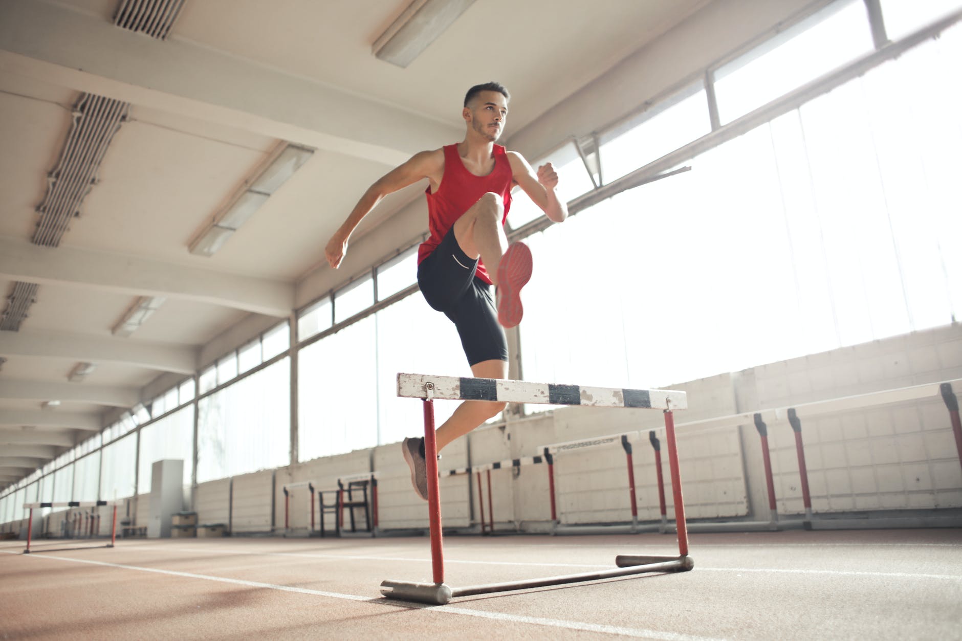 strong young sportsman jumping over barrier