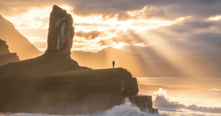 Psalm 61:2 meaning — silhouette on a high rock in morning light above misty waves